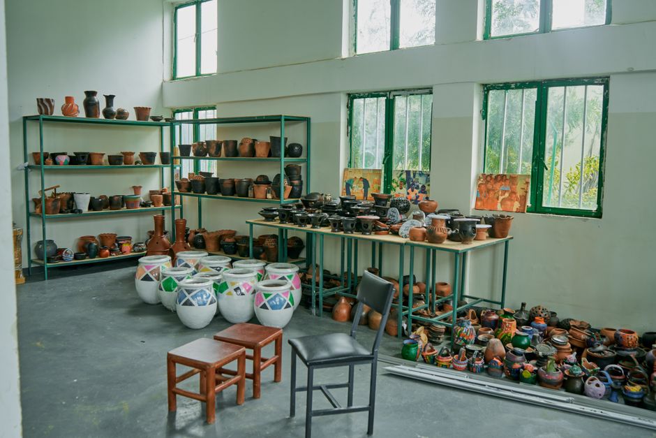 Interior of a pottery studio featuring colorful handmade clay pots and vases displayed on shelves and tables.