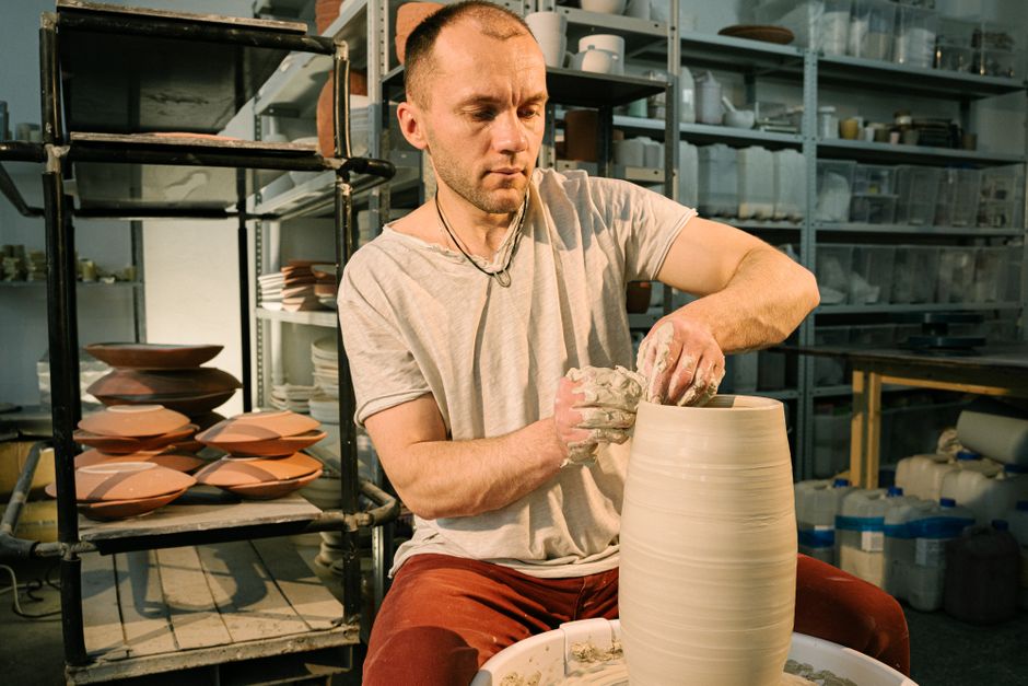 An artisan focuses on crafting a clay pot in an indoor pottery studio, showcasing traditional craftsmanship.