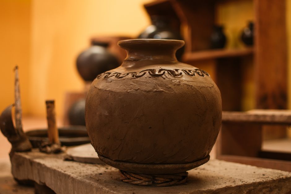 Close-up of a handcrafted clay vase in a warm-toned pottery workshop setting.
