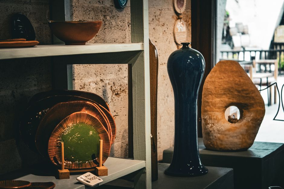 Showcase of artistic ceramic vases and plates in a rustic indoor setting.
