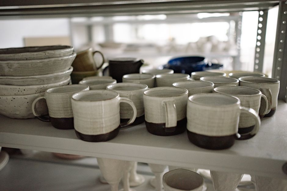 Close-up of artisan-crafted ceramic mugs on a shelf, showcasing pottery craftsmanship.